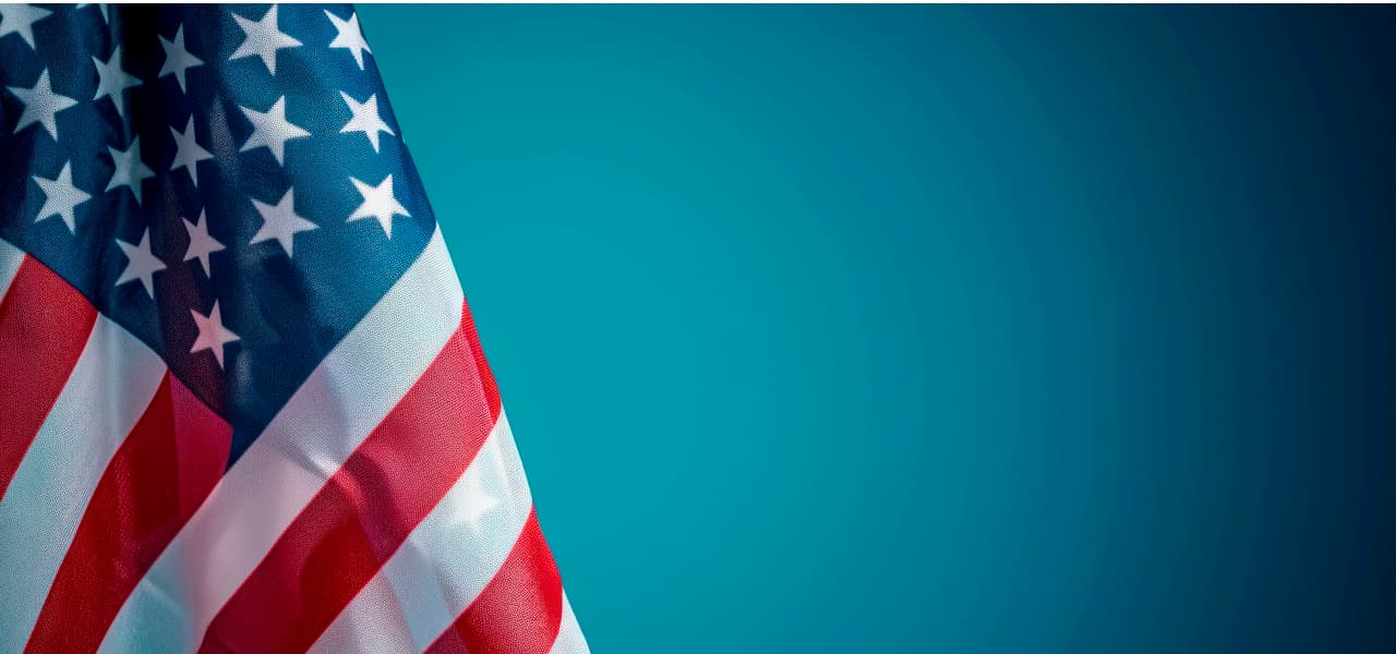 USA | Motiv ©Hunman - stock.adobe.com | © stock.adobe.com, September 2024 Amerikanische Flagge vor blauem Hintergrund. | Motiv ©Hunman - stock.adobe.com | © stock.adobe.com, September 2024