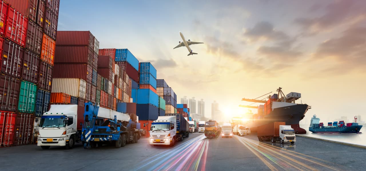 A Artikel Warenverkehr (jpg) | Motiv ©Travel mania - stock.adobe.com | © stock.adobe.com, November 2022 Containerfracht mit LKWs am Hafen. Am Himmel fliegt ein Flugzeug. | Motiv ©Travel mania - stock.adobe.com | © stock.adobe.com, November 2022
